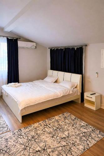 a bedroom with a large white bed with a rug at Nesto Rooms in Sighetu Marmaţiei