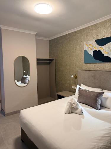 a bedroom with a large white bed and a mirror at Eden Hotel on Florida in Durban