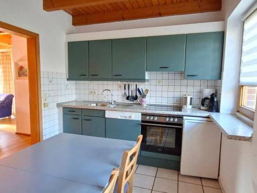 a kitchen with green cabinets and a table at Haus 24 im Natur Ferienpark, Perfekt für Hundeliebhaber, Wanderfreunde und Naturliebhaber in Nieheim