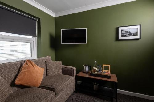 a living room with green walls and a couch and a table at Old Ship Inn Hackney in London