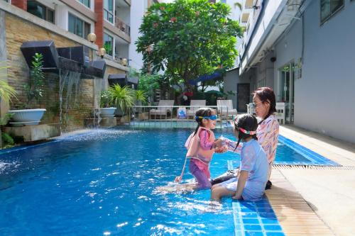 a woman and two children playing in a swimming pool at Kokotel Pattaya South Beach in Pattaya
