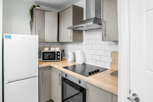 a kitchen with white cabinets and a stove top oven at Family-Friendly Chorlton Apartment with Free Street Parking in Sale