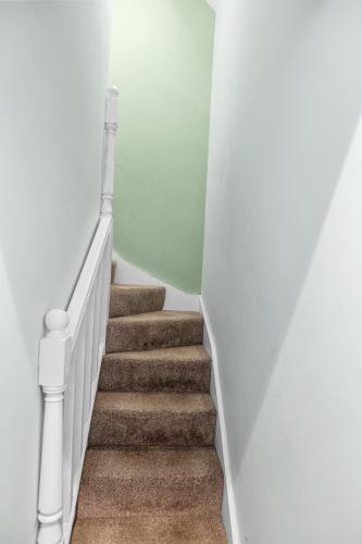 a staircase with white walls and carpet at Family-Friendly Chorlton Apartment with Free Street Parking in Sale