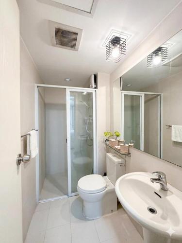 a white bathroom with a toilet and a sink at Metro Manila Cityscape Charm at Azure Urban Resort Paranaque near NAIA Airport in Manila