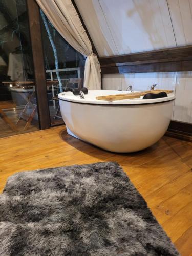 a white bath tub sitting on a wooden floor at Chalé Malbec, Estrada do Vinho com cafe da manha e hidro in São Roque