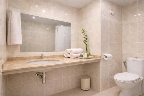 ein Badezimmer mit Waschbecken, Toilette und Spiegel in der Unterkunft Prestige Grand Hotel & Aquapark - All Inclusive in Goldstrand
