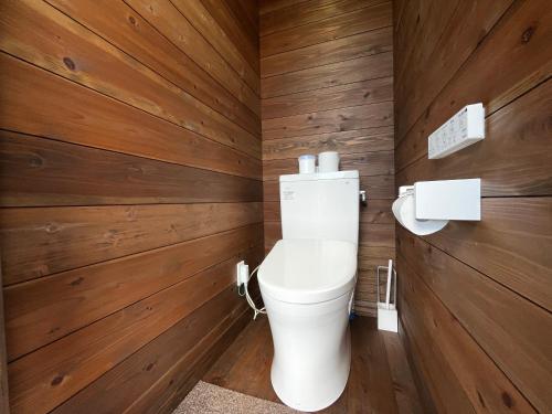 a bathroom with wooden walls and a toilet at Bungee Inn in Minamiizu