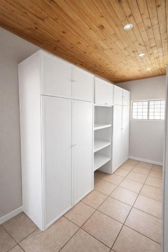 an empty room with white cabinets and a wooden ceiling at Work, Rest, Repeat, Comfortable 2BR Flat in Kathu in Kathu