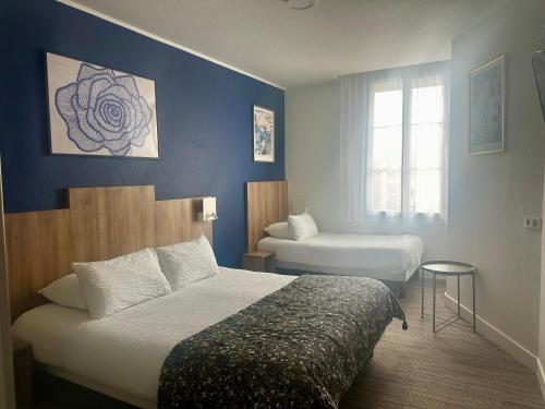 a hotel room with two beds and a window at Logis Hôtel Maison Voltaire in Amboise