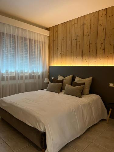 a bedroom with a large white bed with wooden walls at da Tony home B&B in Tarzo