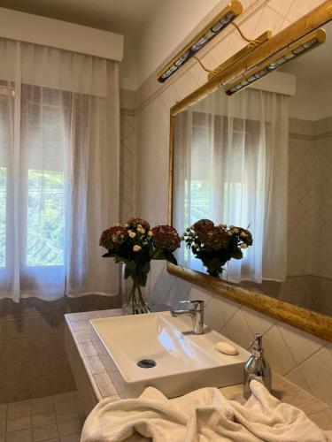 a bathroom with a sink and a mirror and flowers at da Tony home B&B in Tarzo