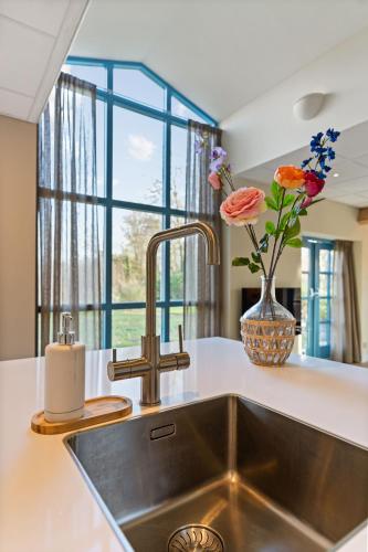 a kitchen sink with a vase of flowers next to a window at Boerderij appartement 't Vogelnest in Heiloo