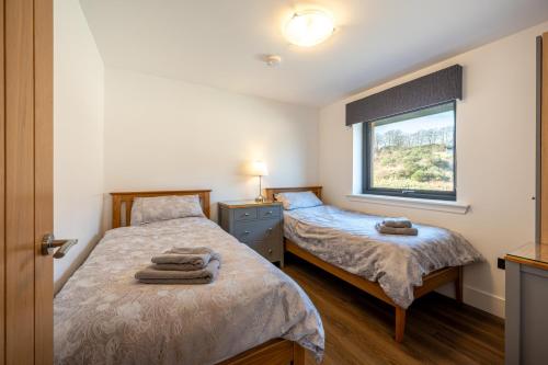 two beds in a room with a window at Annabella Cottages in Crossford