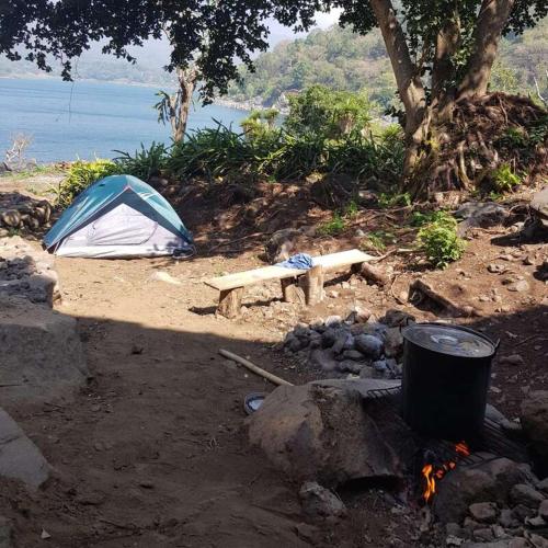 a tent and a bench next to a camp fire at Patziapa in Santiago Atitlán