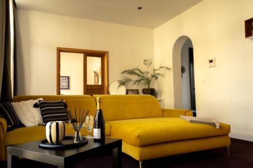 a living room with a yellow couch and a table at Sur un air d'eau in Spa