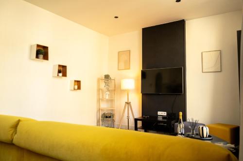 a living room with a yellow couch and a tv at Sur un air d'eau in Spa