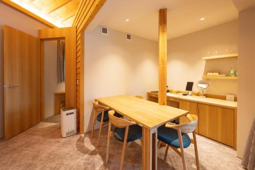 a dining room with a wooden table and chairs at ヴィラブラマーレ in Kitahiroshima