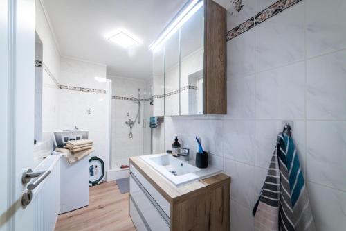 a white bathroom with a sink and a refrigerator at Ferienwohnung TaJoLe in Heinade