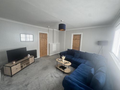 a living room with a blue couch and a tv at Grieve Apartment in Jedburgh