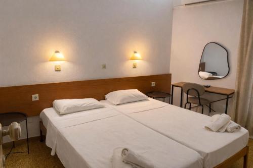ein Schlafzimmer mit einem großen weißen Bett und einem Spiegel in der Unterkunft Pasiphae Self Hotel in Heraklion