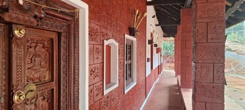 a red building with a wooden door and a corridor at Srikadhama in Udupi