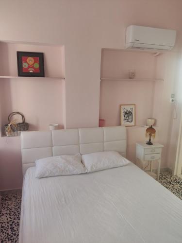 a bedroom with a white bed with a white headboard at Angel House in Ermoupoli