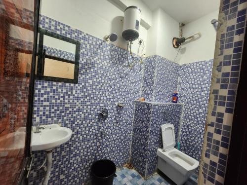 a blue tiled bathroom with a toilet and a sink at SRT Homes Ranchi in Rānchī