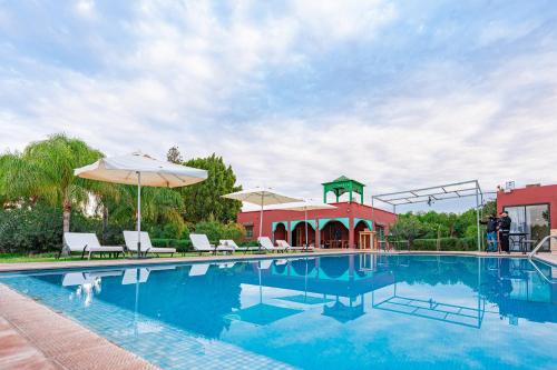 a swimming pool with chairs and umbrellas next to a building at Bungalow with Pool View & Breakfast in Marrakesh