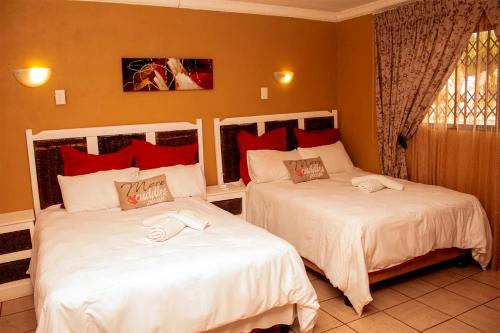 two beds in a bedroom with red pillows at Amazing Grace Inn BnB in East London