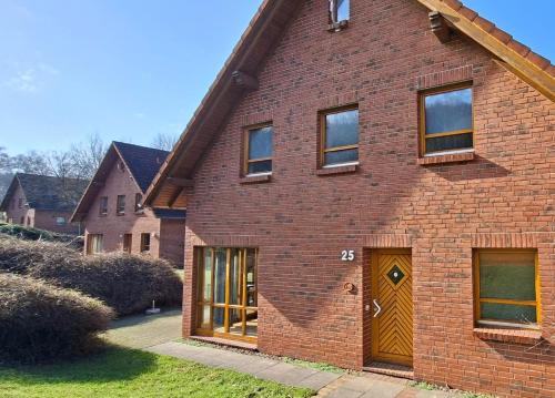 a brick house with a brown door and a yard at Haus 25 im Natur Ferienpark, Erlebnisurlaub mit Action, Radfahren und Wanderabenteuern im Grünen in Nieheim