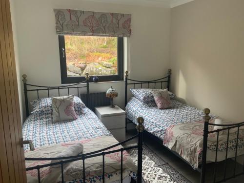 a bedroom with two beds and a window at Carrick Chalets in Cairndow