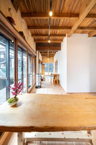 a large wooden table in a room with windows at 長浜ゲストハウスミカタ Guest House Mikata in Nagahama