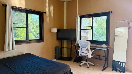 a bedroom with a bed and a desk and two windows at Chill House in Ko Phangan