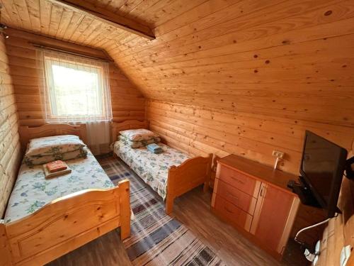 a room with two beds in a log cabin at Садиба У Коса in Pilipets