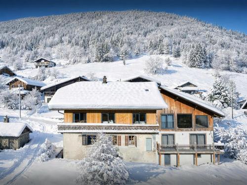 a house is covered in snow with a mountain at La Grange Neuve - OVO Network in Saint-Jean-d'Aulps