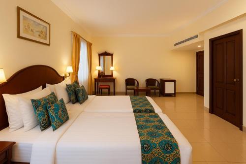 a bedroom with a large white bed with green pillows at Hotel Indraprastha Thiruvalla in Talavadi