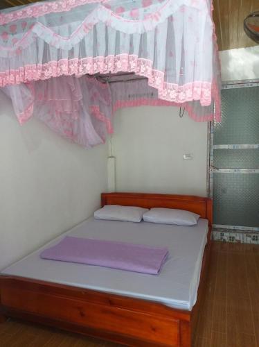 a small bed in a room with a pink curtain at Quang Hưng Hommestay in Pac Ngoi