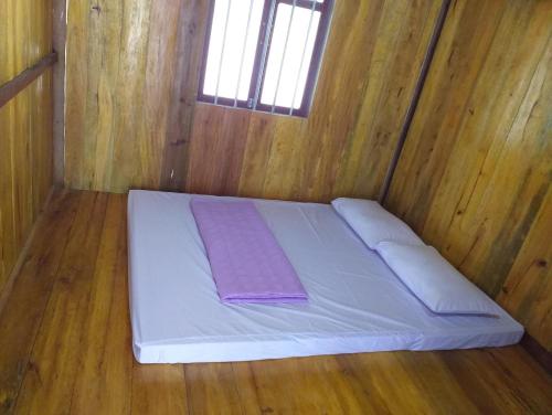 a white bed in a wooden room with a window at Quang Hưng Hommestay in Pac Ngoi