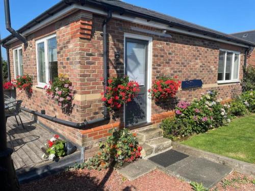 a brick house with flowers in front of a door at Stylish Morpeth Cottage with Log Burner, Garden and Free Parking in Morpeth