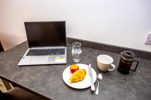a laptop computer sitting on a table with a plate of food at The Calf House in Sibbertoft