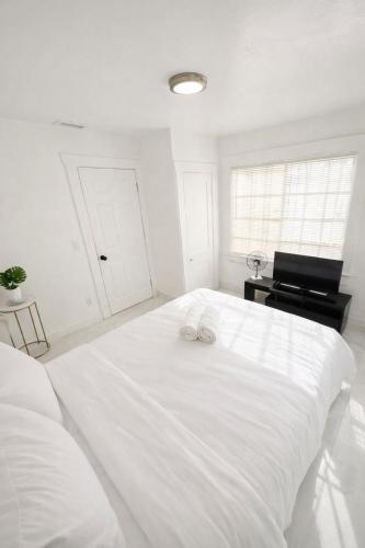 a white bedroom with a large white bed and a piano at Omaha Wynwood in Miami