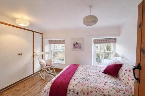 a bedroom with a bed and a chair and windows at Pen Llyn Quarryman's Cottage in Trevor