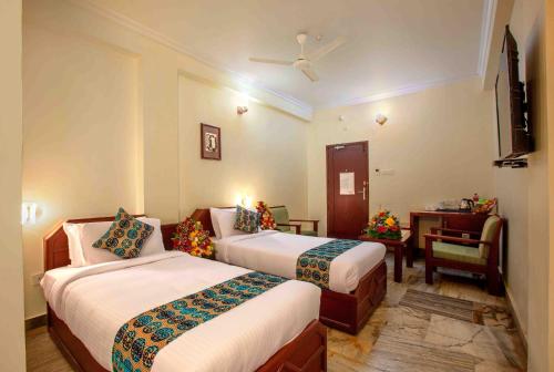 a hotel room with two beds and a desk at Hotel Indraprastha Karunagapally in Panmana