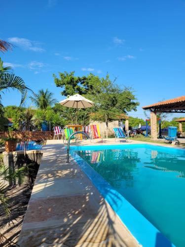 a swimming pool with an umbrella and chairs at Casa em condominio com piscina na beira do rio Alegre in Santo Amaro