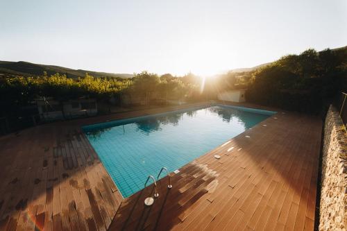 a large blue swimming pool with the sun in the background at Vall d'Àger Resort & Camping in Àger