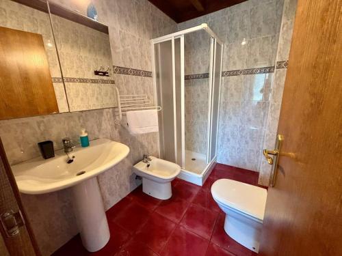 a bathroom with a sink and a toilet and a shower at Chalet con jardín junto a playas in Colunga