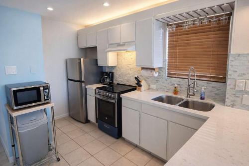 a kitchen with white cabinets and a sink and a microwave at Beach Access Condo with Pool, Hot Tub Area & BBQ - Gulfview I - unit 213 in South Padre Island