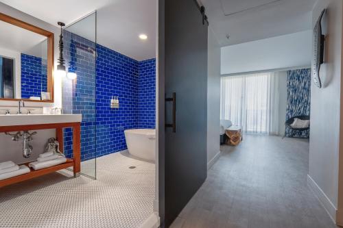 a bathroom with a tub and a toilet and blue tiles at Angler's Hotel - Miami Beach in Miami Beach
