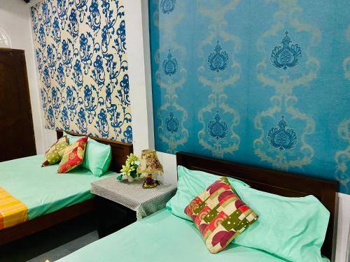 two beds in a room with blue and white wallpaper at VD Rest Gampola in Gampola