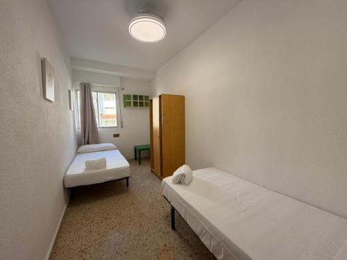 a small room with two beds and a window at Wimpy Solo Familias Serviplaya in Playa de Xeraco